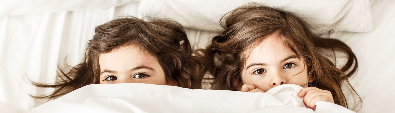 two girls playing hide and seek under a blanket with the camera