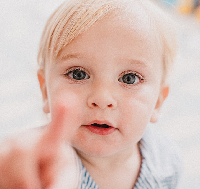 Toddler looking at the camera while pointing at it