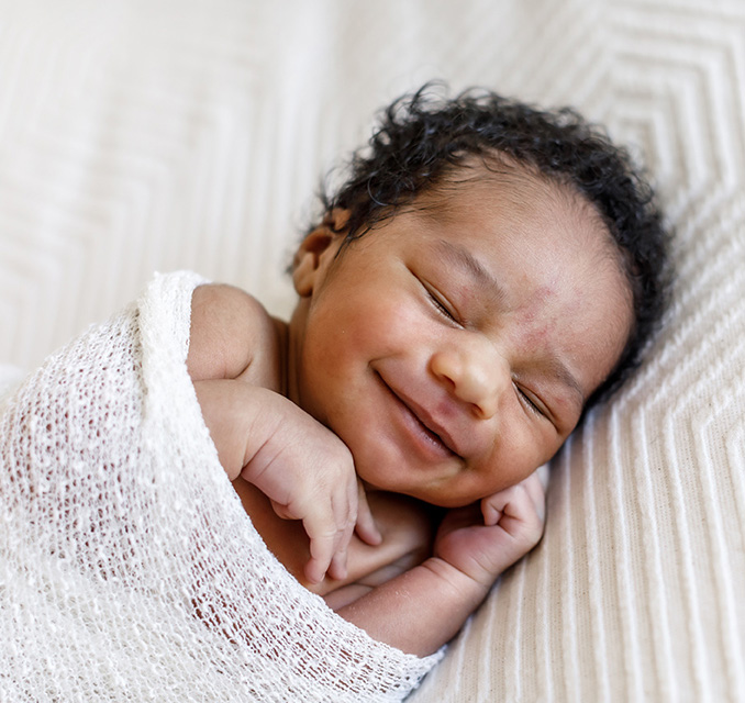 Sleeping newborn baby smiling