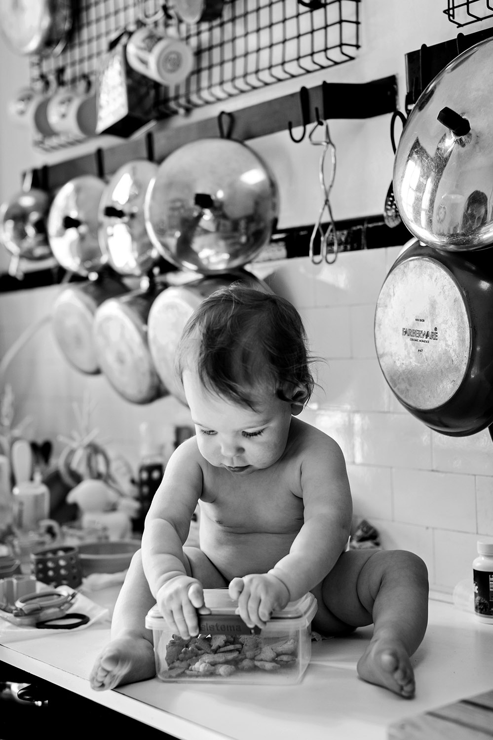 Baby sitting on the kitchen counter holding a box of cookies