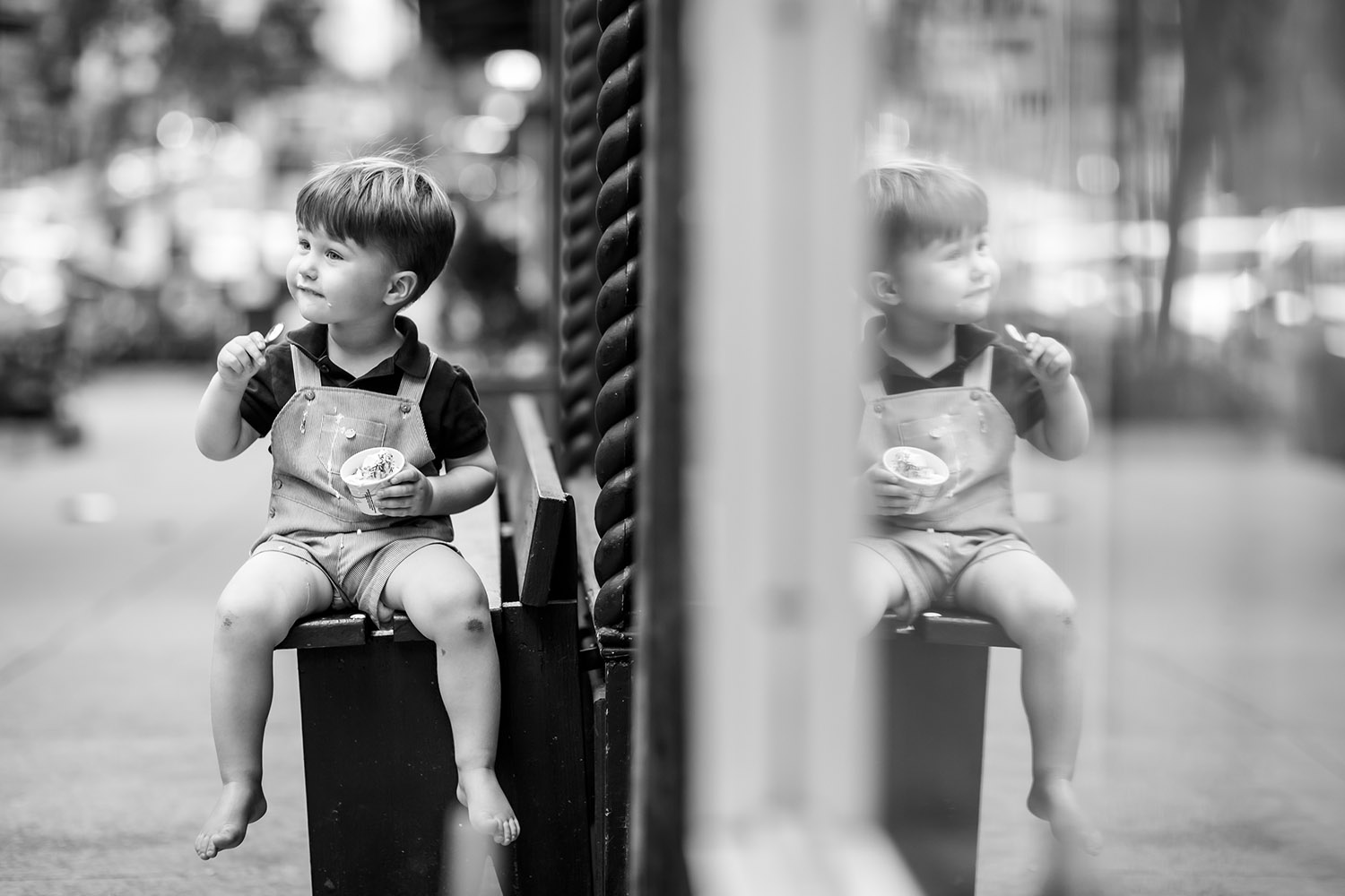 BW Little Boy sitting on a bench while eating ice cream
