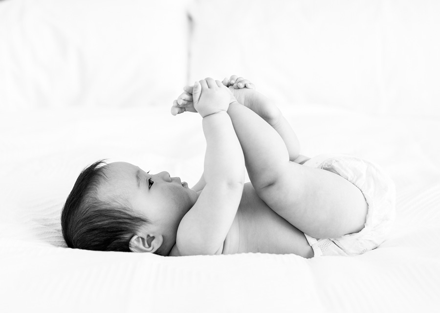 BW Baby holding its feet laying in bed