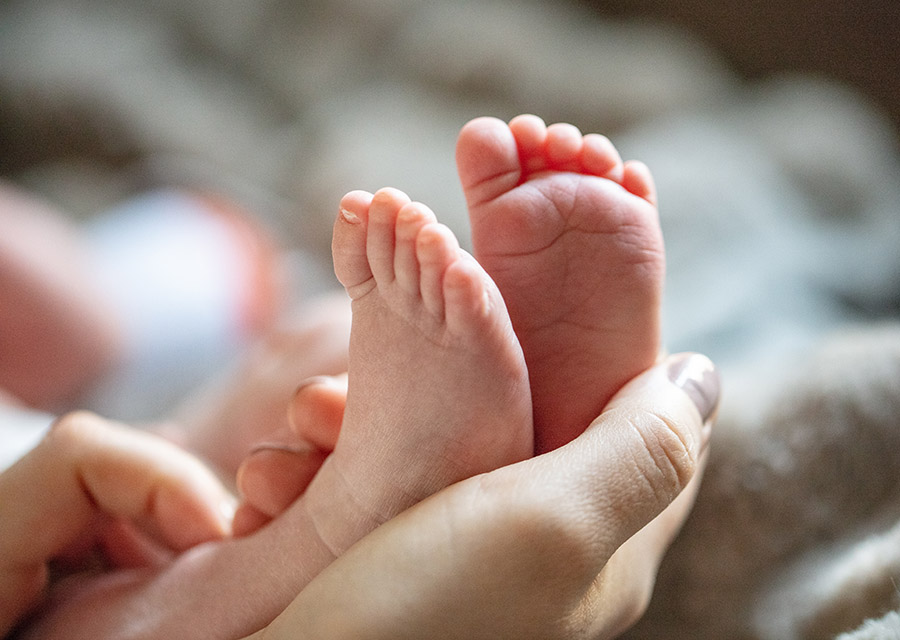 Newborn baby's feet in the mothers hands