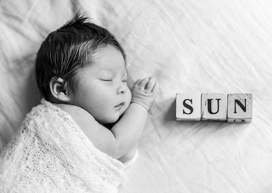 BW Smiling newborn baby next to blocks with letters