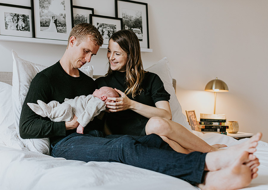 Parents sitting on a bed holding their newborn baby