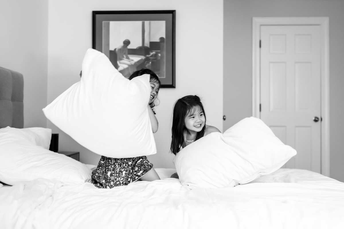 BW Sisters on a bed having a pillow fight