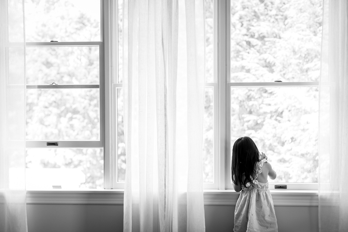 BW Little girl looking outside a window