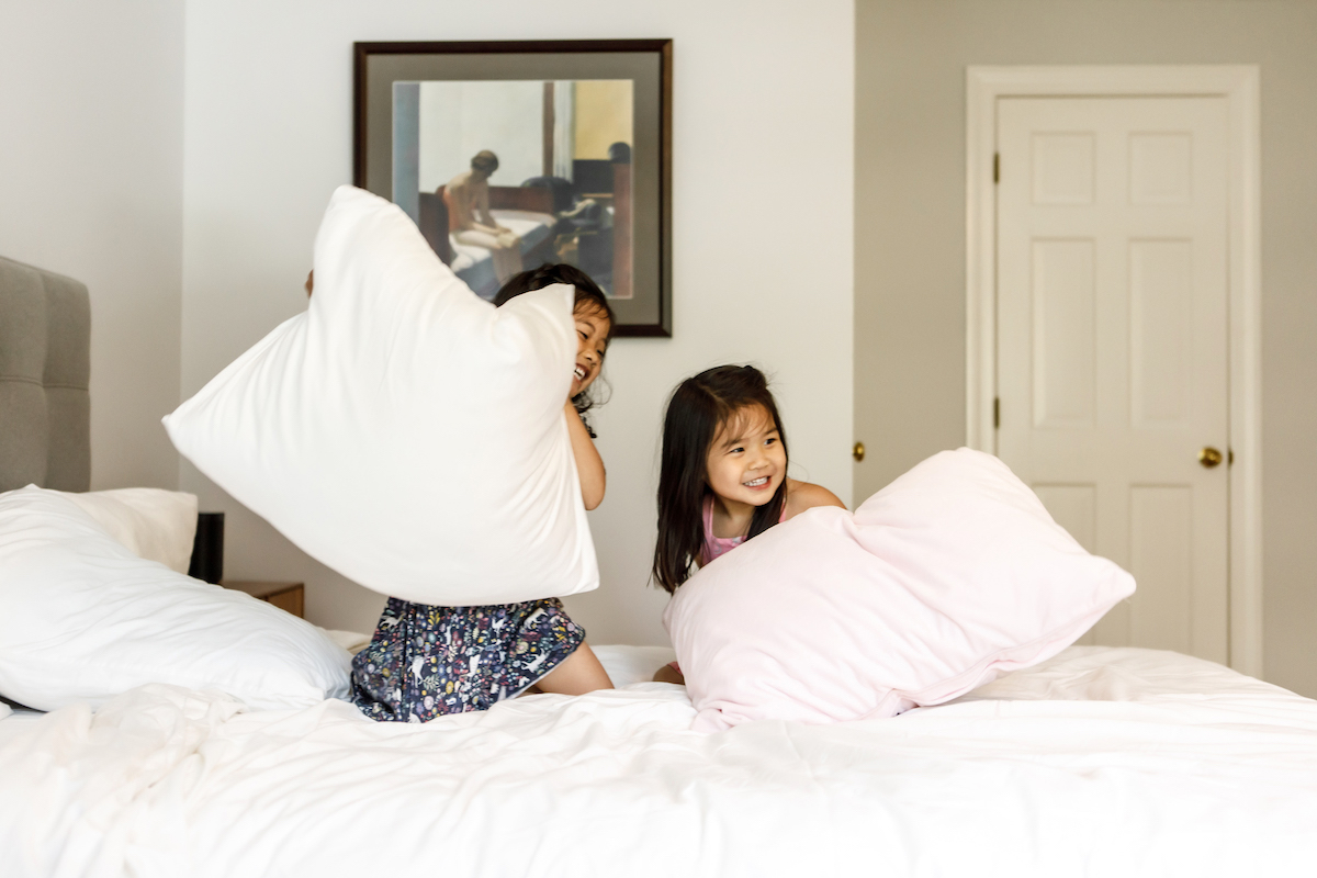 Sisters on a bed having a pillow fight