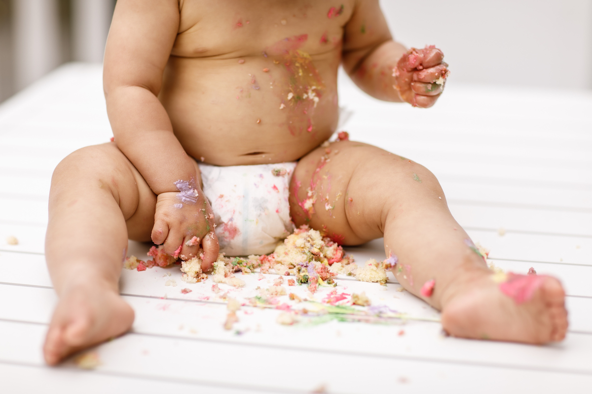 Toddler eating cake close up of belly and feet