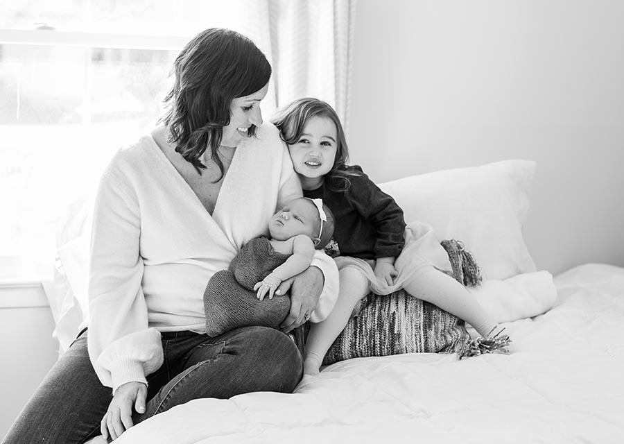 BW Mom with her two daughters on a bed
