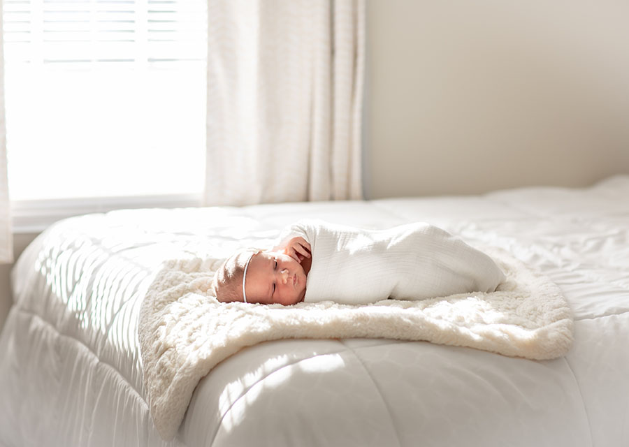 Newborn baby laying on a bed