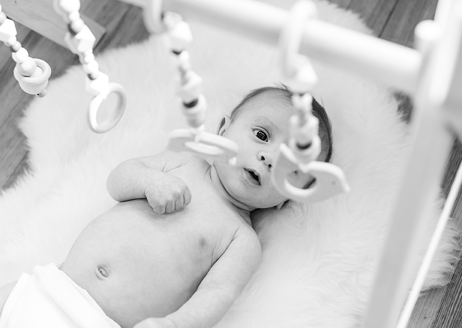 BW top view of a newborn in crib looking up to toys