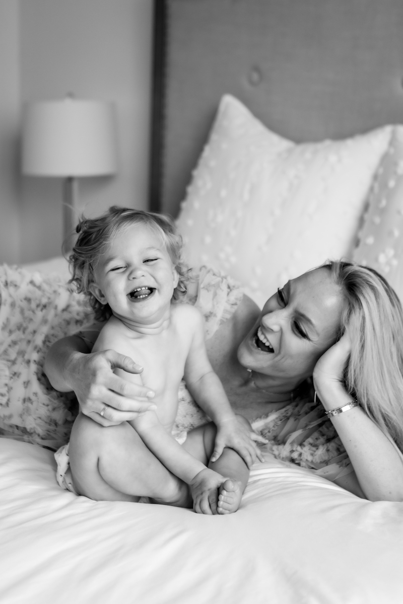 Mom and toddler laughing on a bed