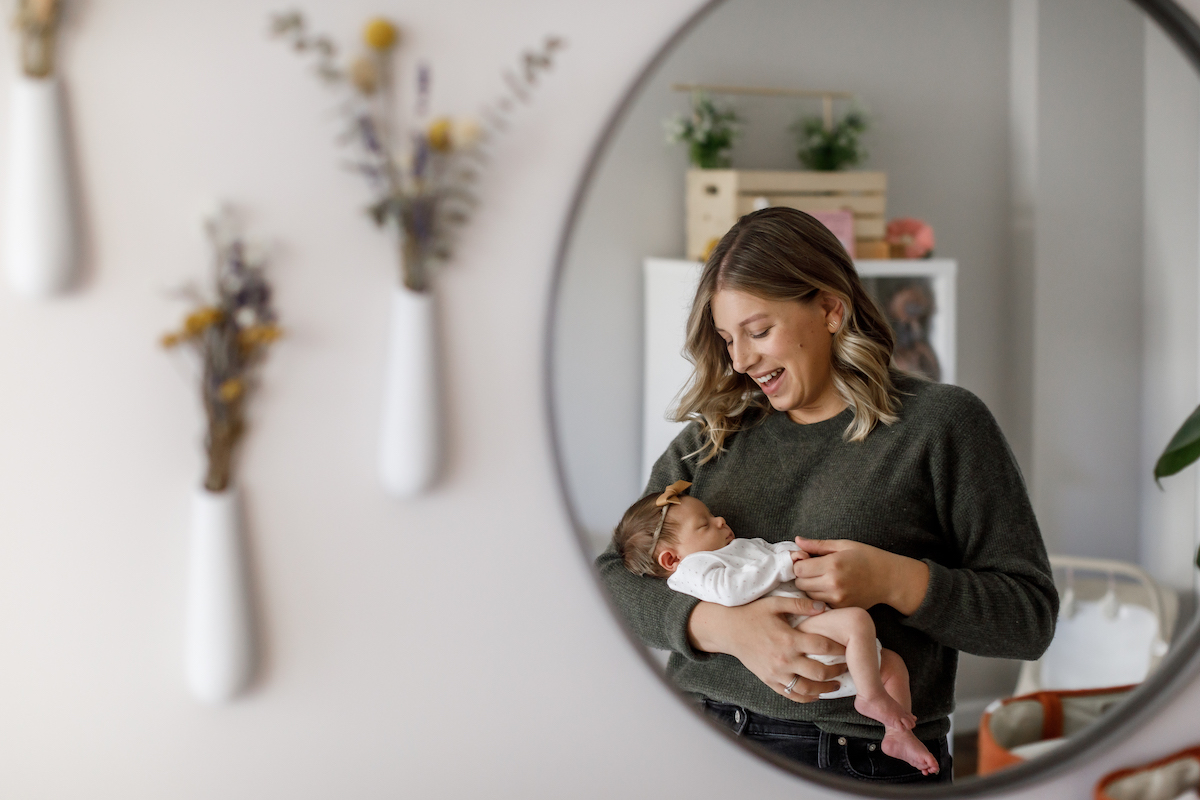 Mom in the mirror holding her newborn baby