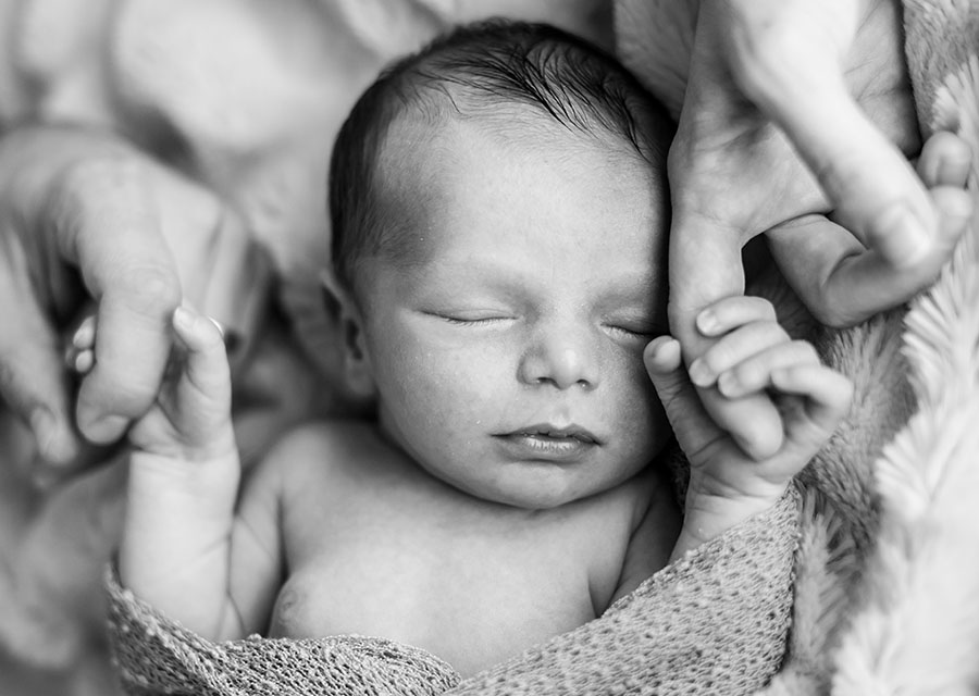 BW Sleeping newborn baby holding mom and dads fingers