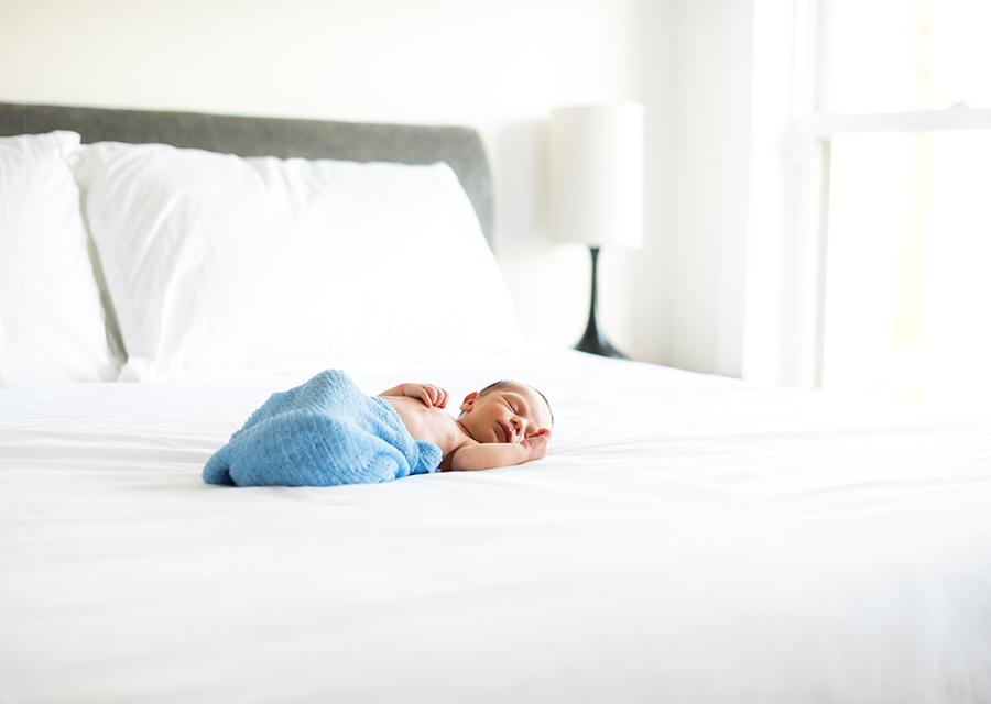 Sleeping newborn baby laying on a bed