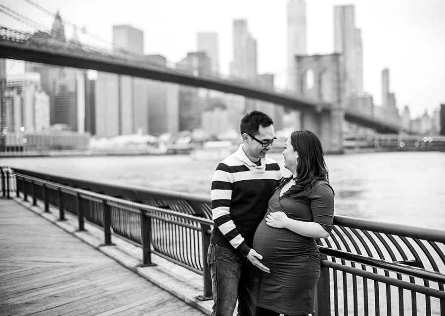 BW Parents-to-be smiling at each other while holding the baby bump