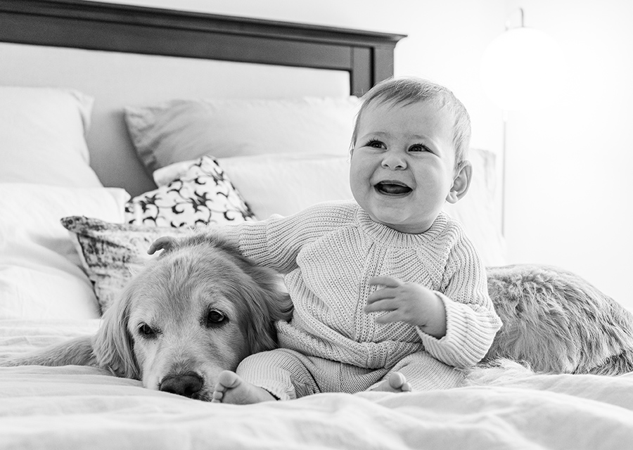 Smiling baby sitting next to a dog