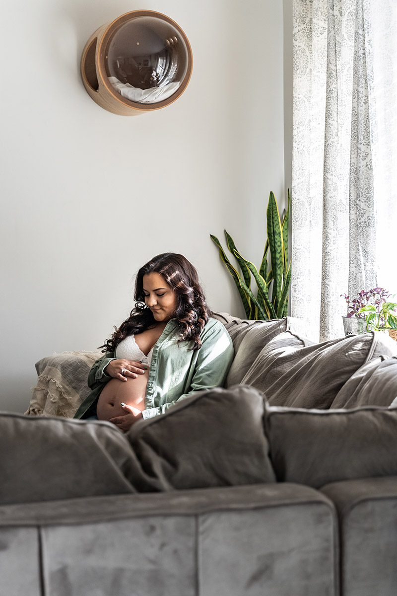 Pregnant woman sitting on a couch holding her belly