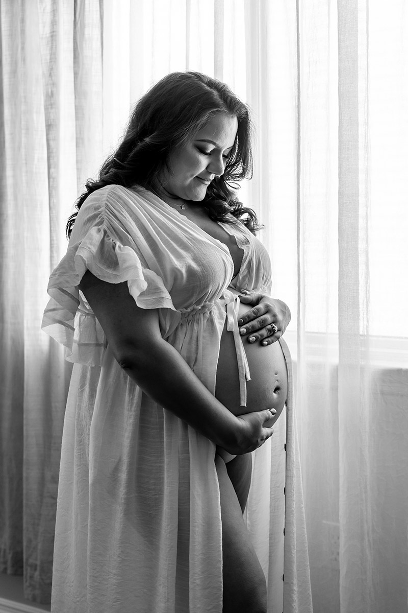 BW Pregnant woman holding her belly while smiling at it