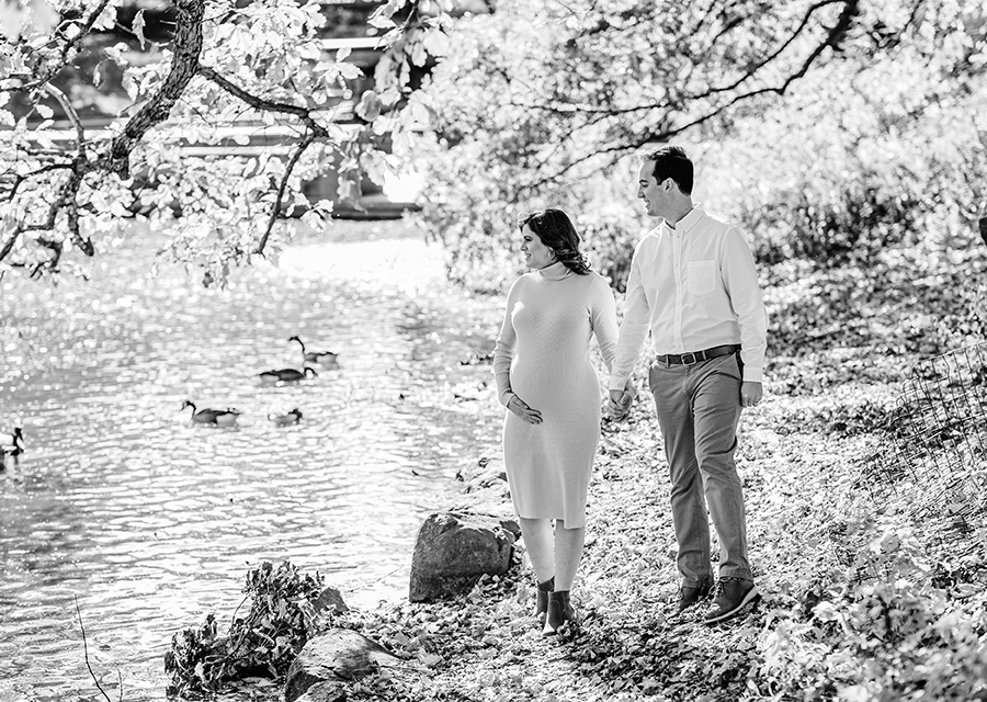 BW Parents-to-be holding hands next to a lake