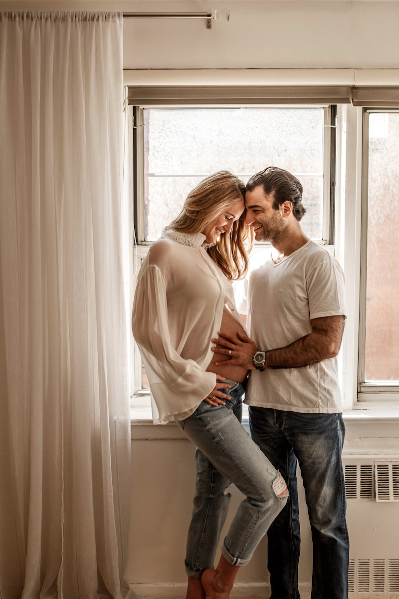 Parents-to-be smiling while holding the baby bump
