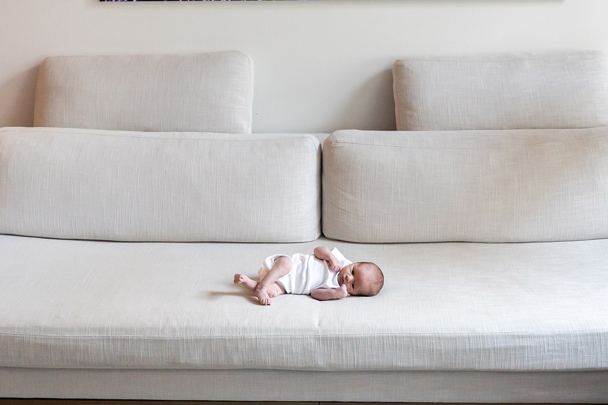 Newborn baby laying on a couch