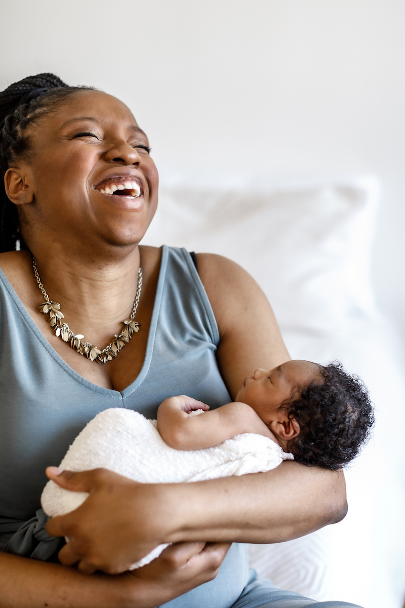 Mom laughing holding her newborn baby