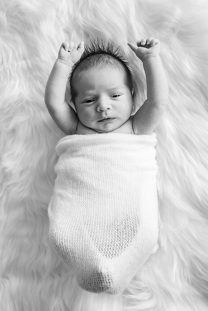 Newborn baby holding his arms up