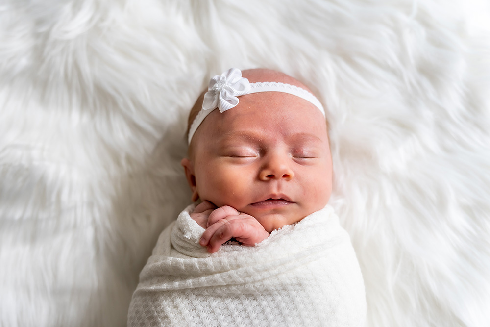 Sleeping newborn baby swaddled in white cloth