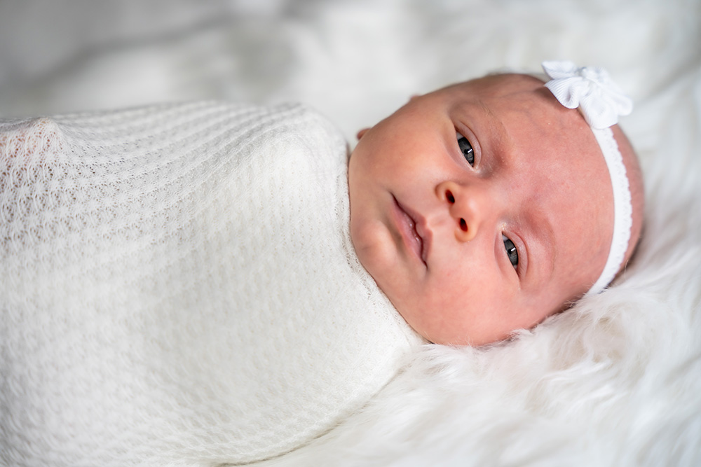 Newborn baby wrapping up on white fur