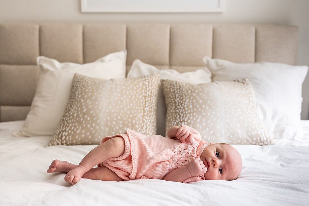 Little baby in pink clothes laying in master bed