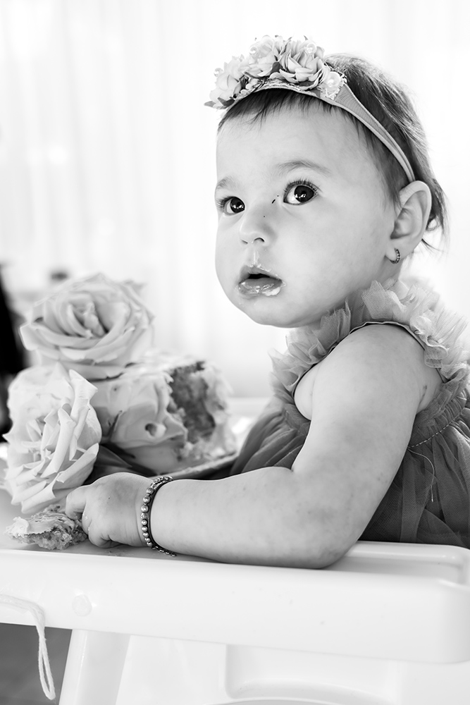 BW Girl with flowers in her hair eating a cake