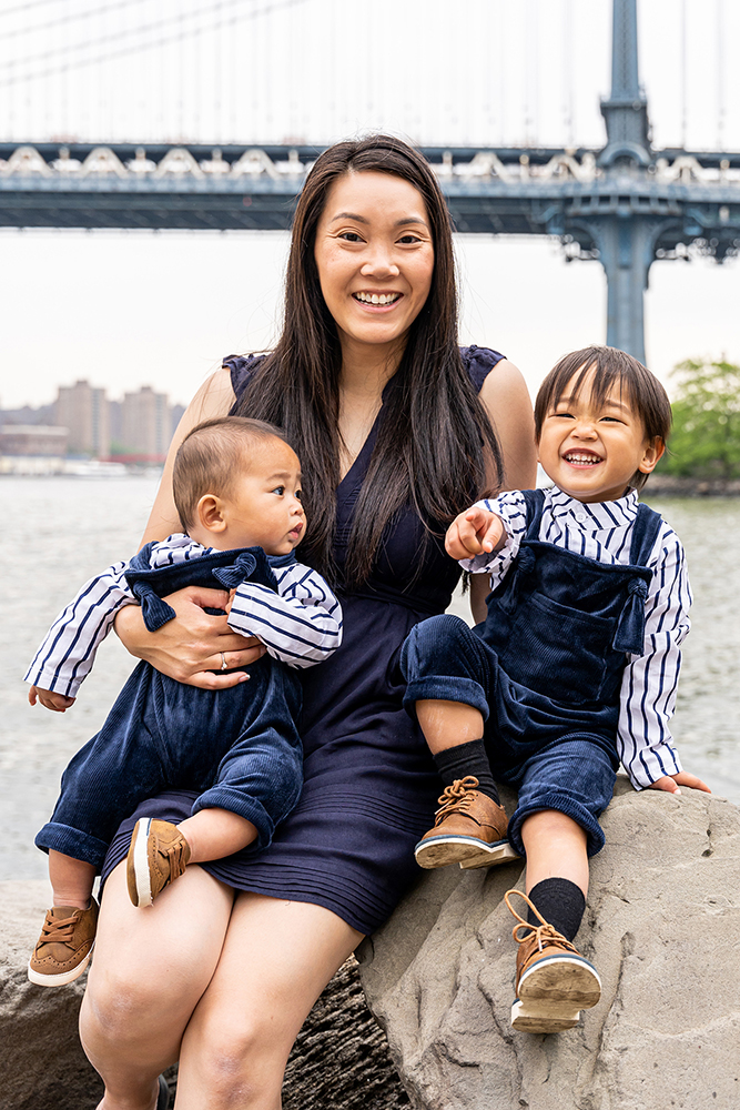 mommy holding their two sons with manhattan bridge in the background