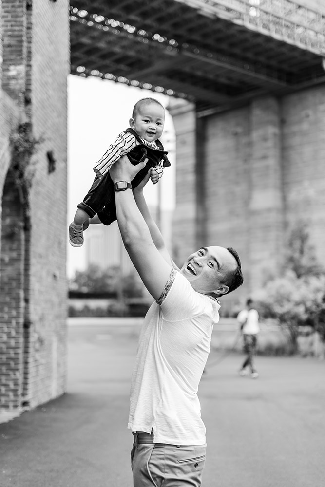 BW Daddy holding his baby son in dumbo near brooklyn bridge