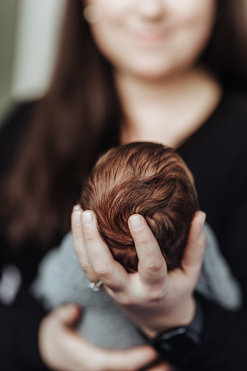 closeup of newborns head held by its mom