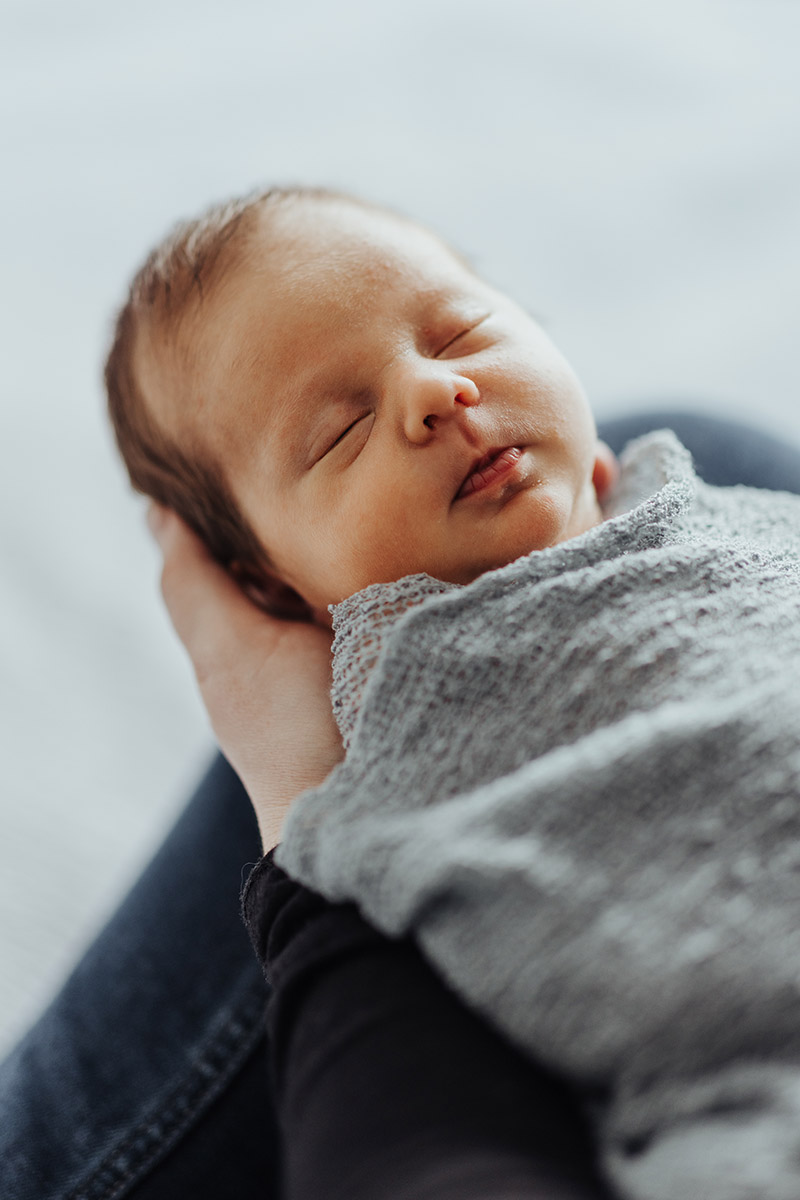 portrait of sleeping newborn held by its mom