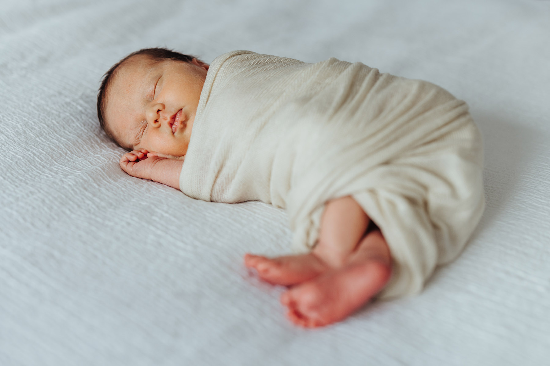 sleeping newborn on white bed sheet