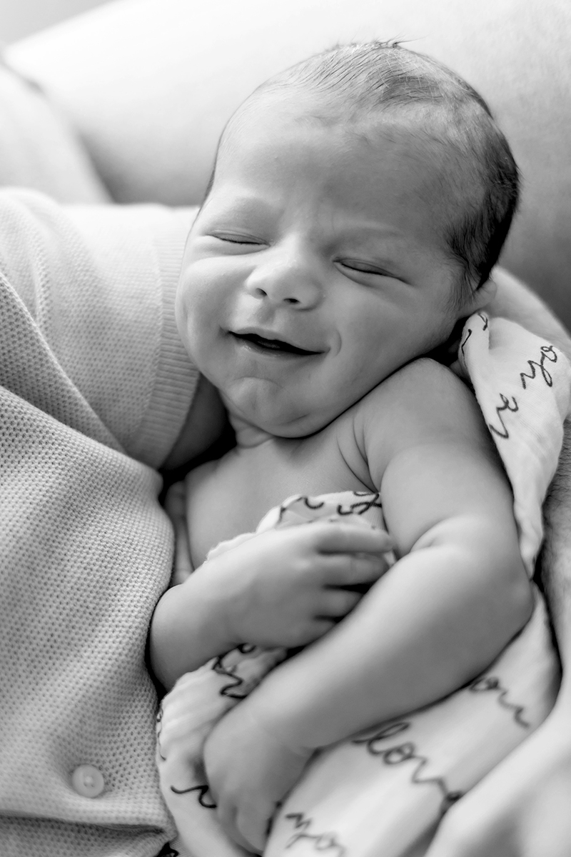 Newborn baby sleeping and smiling into the camera