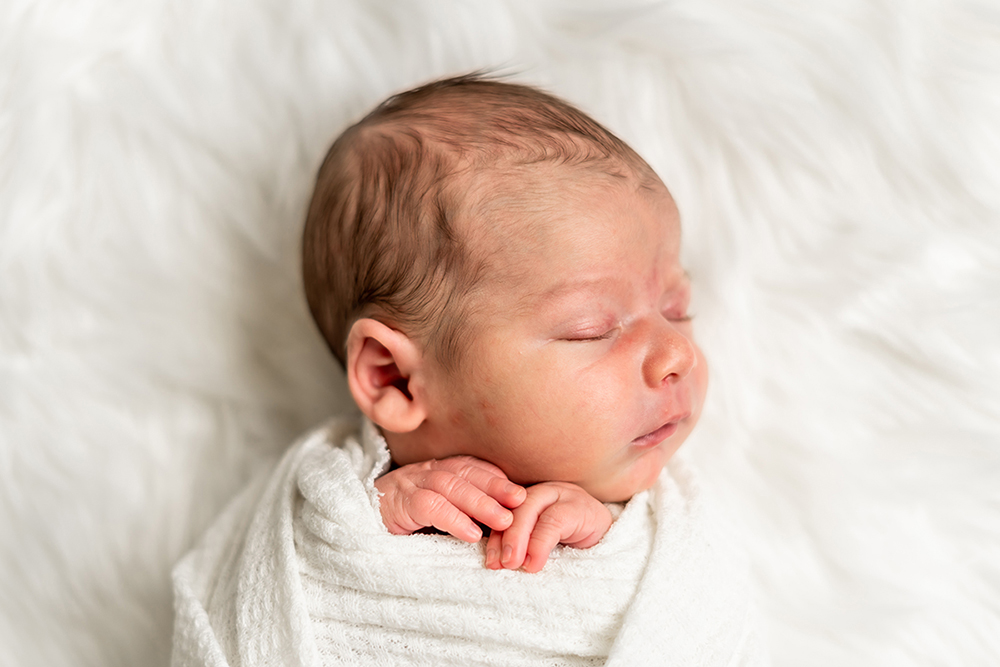 Newborn baby swaddled in white blanket