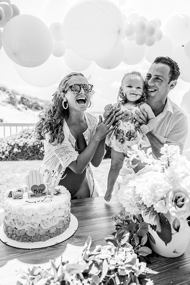 Black and white photo of parents showing their happy daughter the big birthday cake