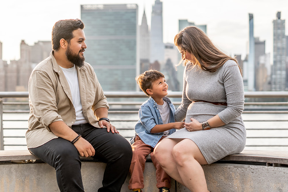 Photo of family with pregnant mom with skyline of Manhattan in the background