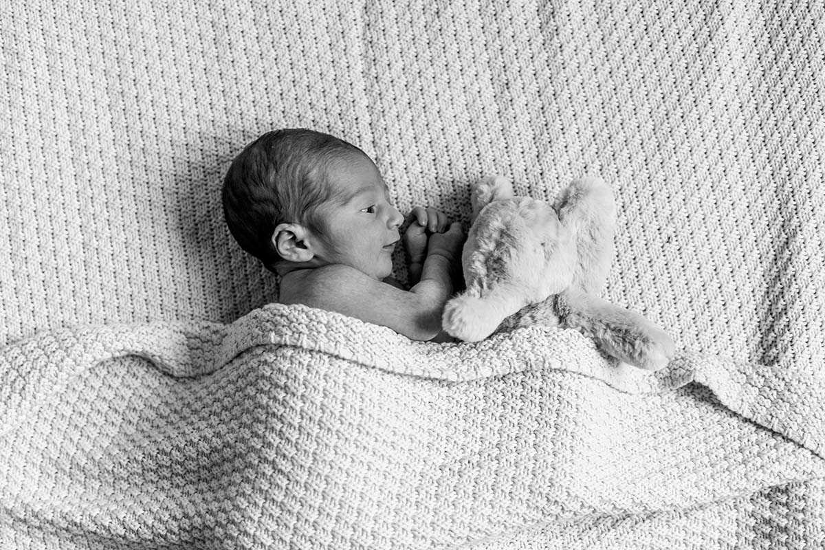 Newborn baby boy cuddling with his stuff animal