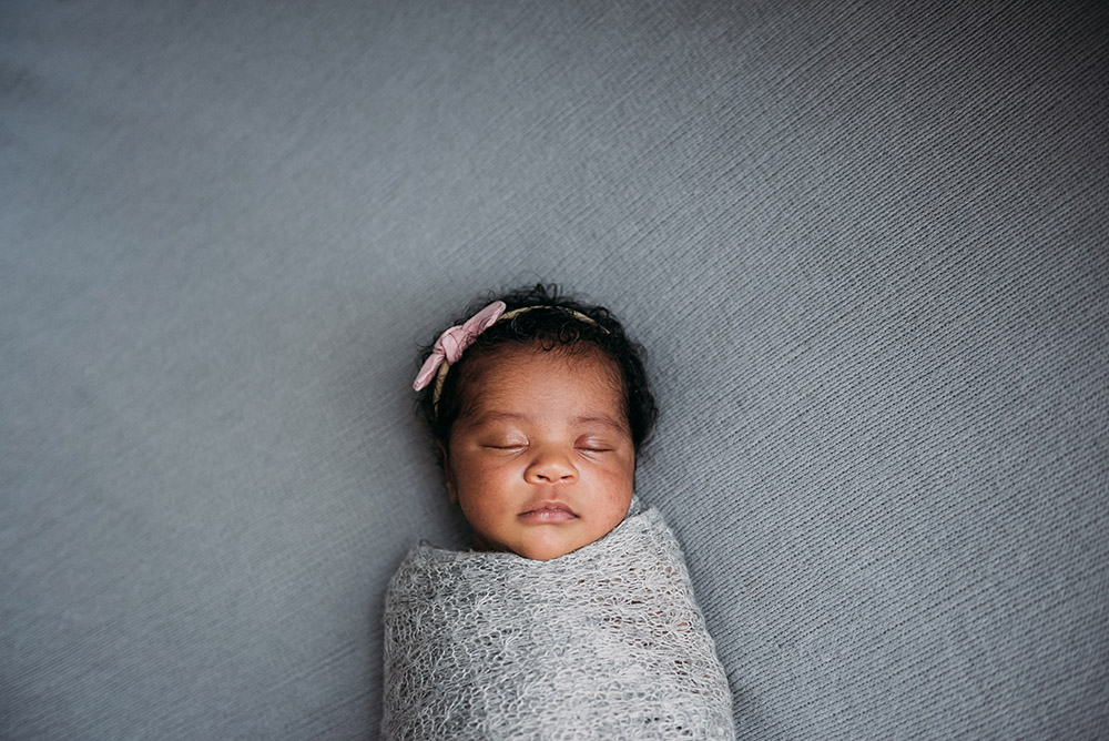 portrait of sleeping newborn laying on grey sheet