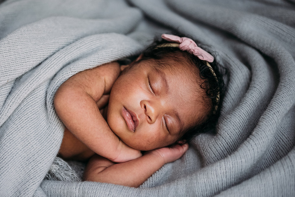 portrait of sleeping newborn with bow in her hair