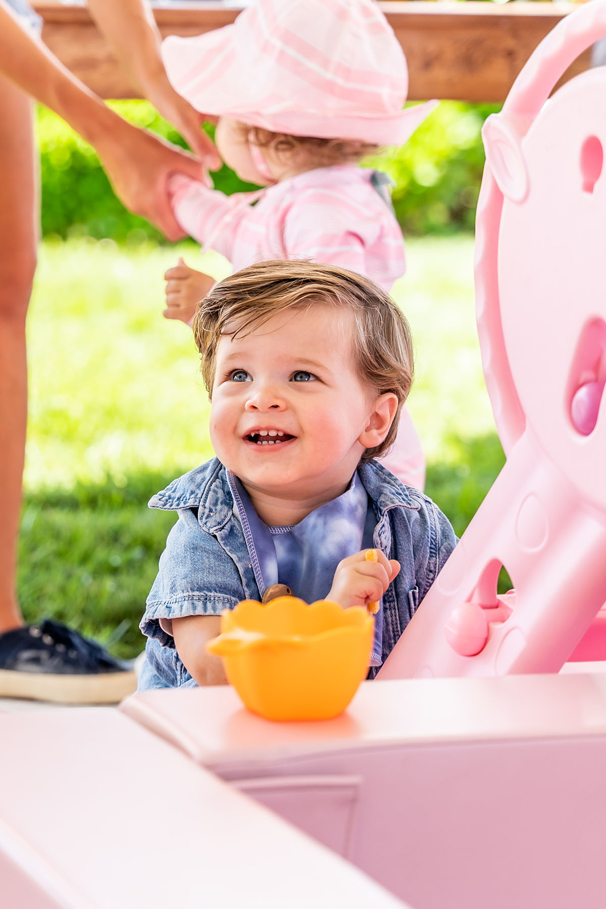 laughing toddler in front of pink sandbox