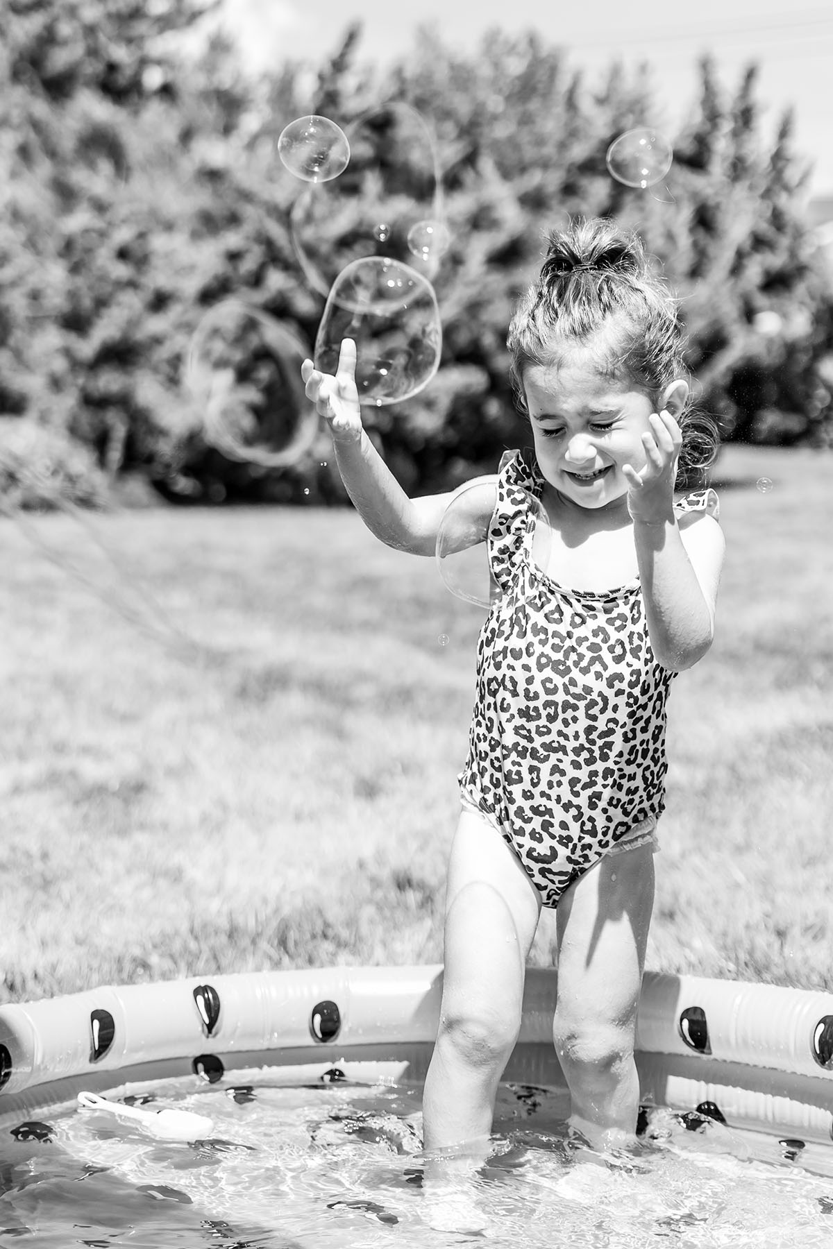 baby girl is playing with bubbles in a pool black and white