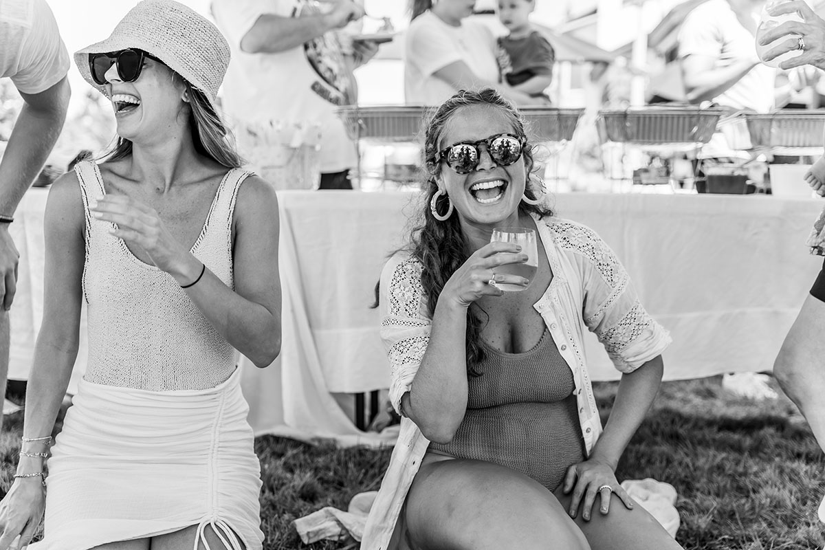 two women are laughing one woman is holding a drink black and white