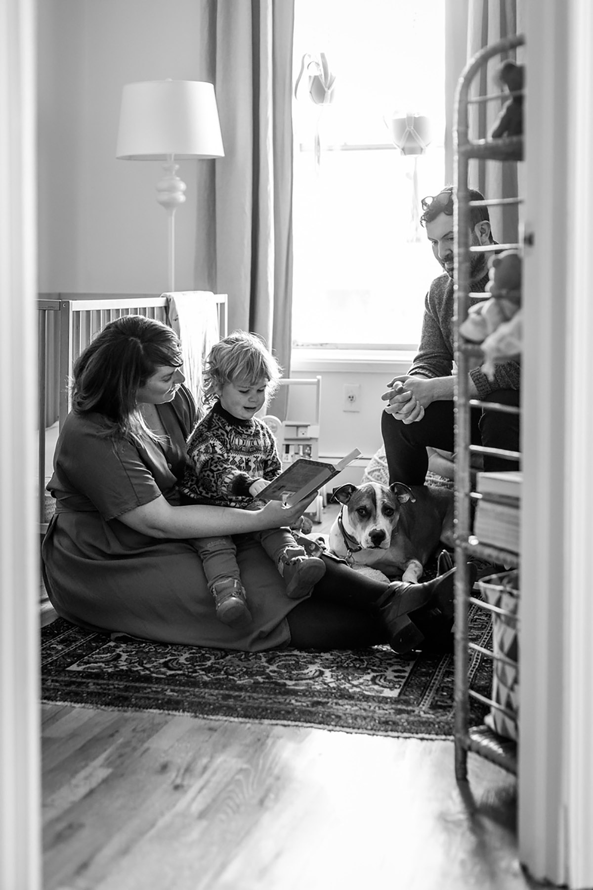 family with dog reading in nursery