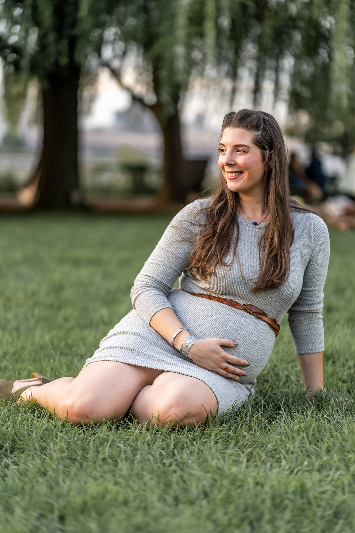 pregnant woman sitting in the grass in hoboken